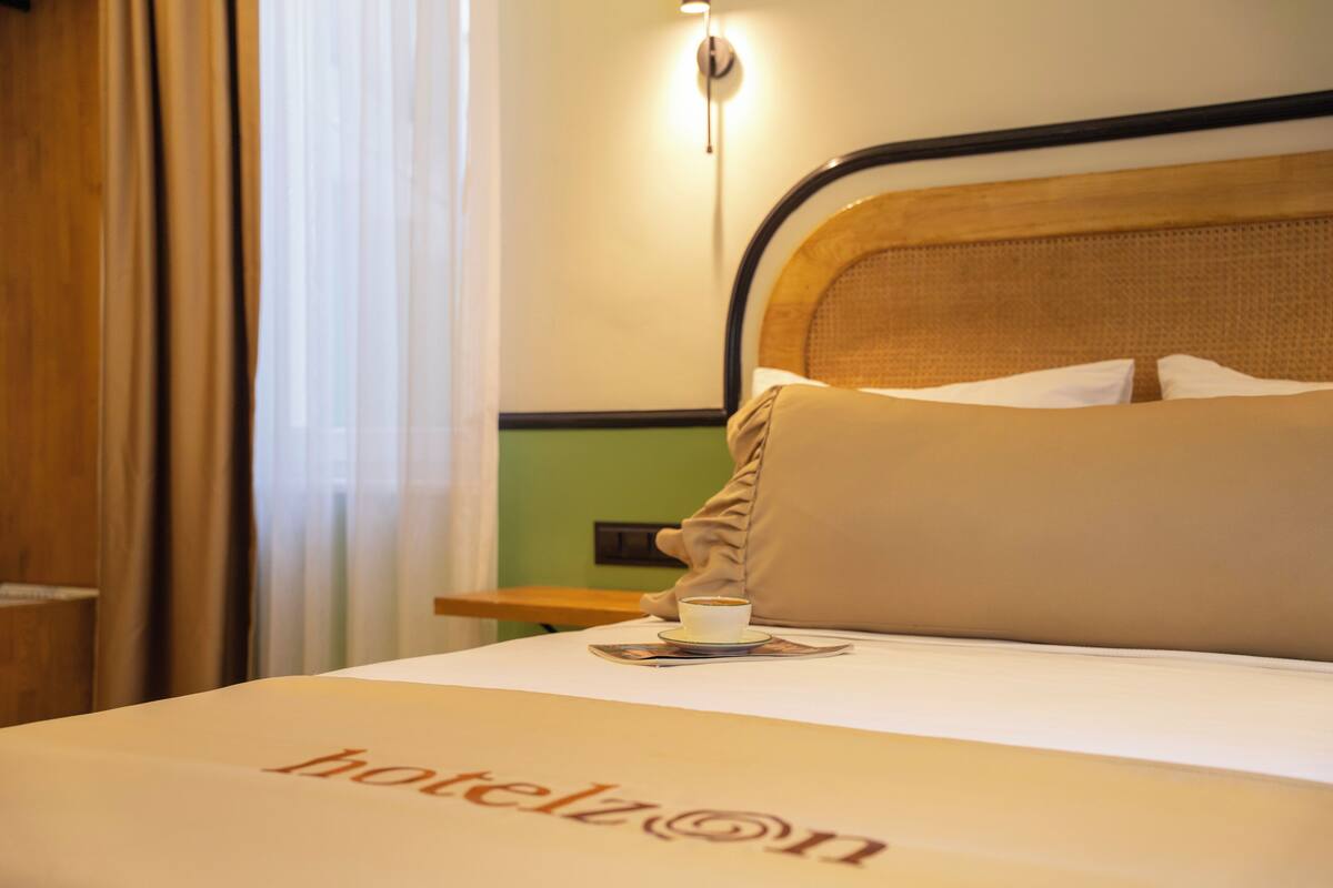 Ein Hotelzimmer mit Bett, Nachttisch, einer Kaffeetasse und einer Lampe.