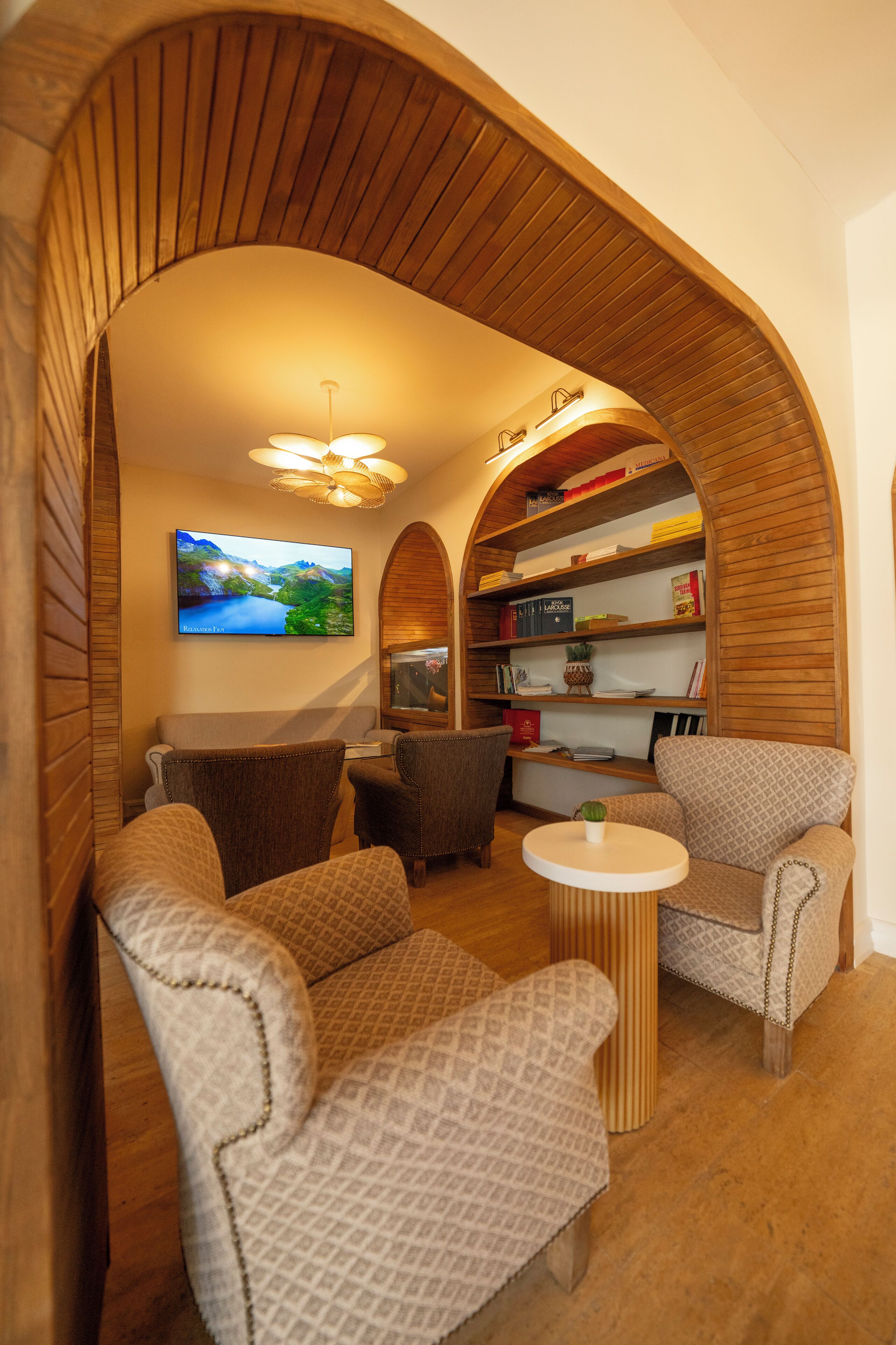 A cozy living room with a fireplace, comfortable seating, a television, and a bookshelf.