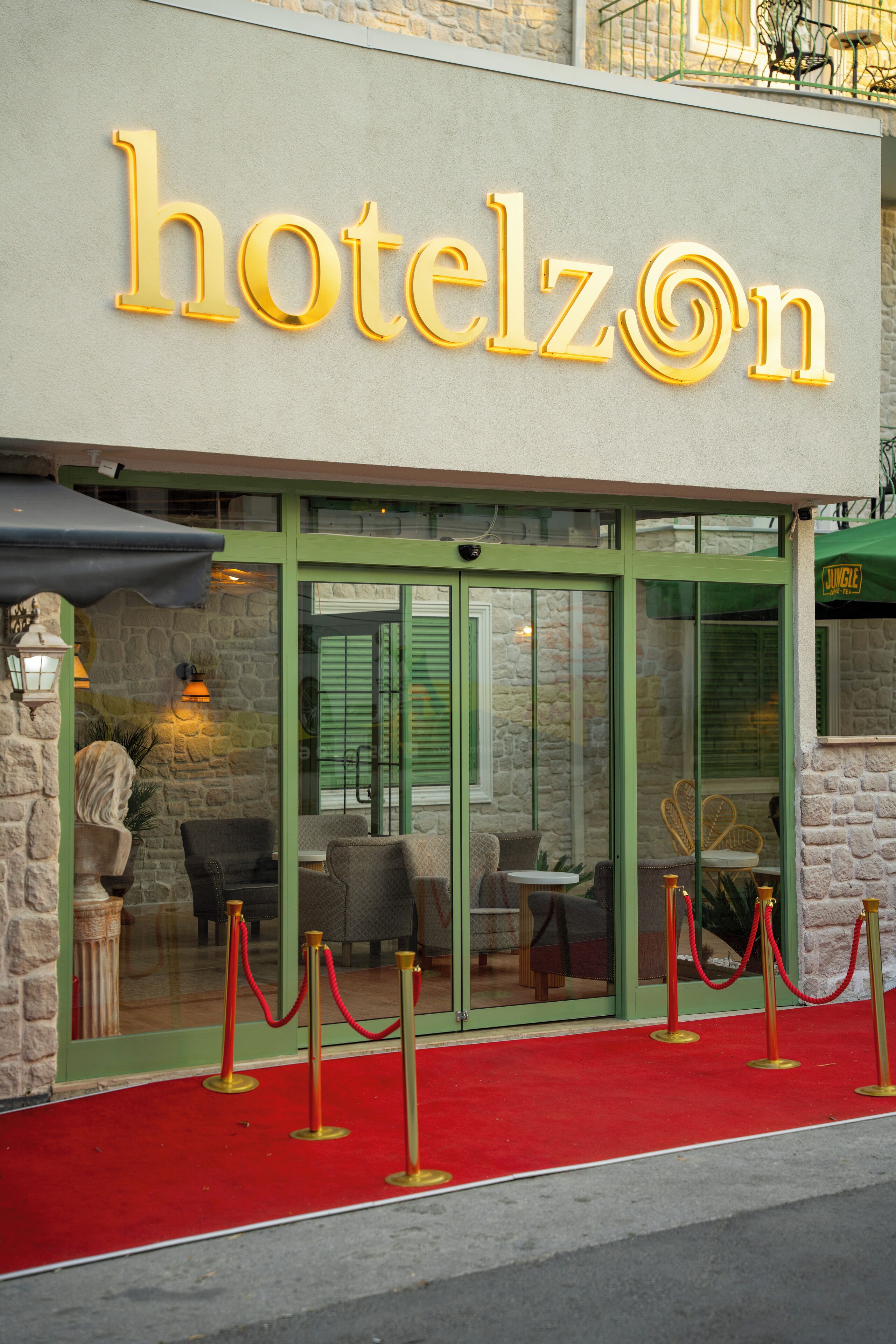 A hotel entrance with a red carpet, glass doors, and a sign reading "hotelzOn".