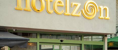 Een hotelentree met een rode loper, glazen deuren en een bordje met de tekst 'hotelzOn'.