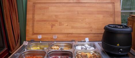 A buffet with various food items and a large black pot, likely for cooking or heating.