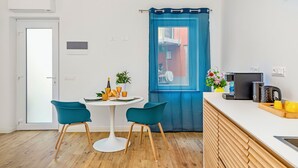 A modern kitchen with a white countertop, two teal chairs, a round table, and a blue curtain. - Lily ancient stone mansion dating back to the 1400s (Volastra)