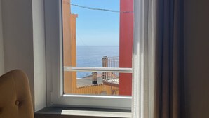 A room with a window overlooking a building with red and yellow colors, a chair, and a power outlet on the wall. - Lily ancient stone mansion dating back to the 1400s (Volastra)
