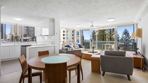 Un apartamento moderno con cocina, comedor y sala de estar, con ventanas amplias que ofrecen vistas a la ciudad.