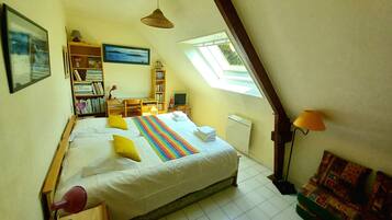 Une chambre à coucher avec un lit, un bureau, une bibliothèque, une télévision et une fenêtre.