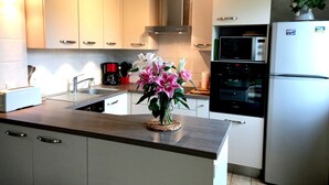 Eine moderne Küche mit weißen Schränken, Edelstahlgeräten und einem Blumenstrauß auf der Arbeitsfläche.