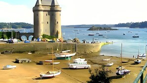 Eine Küstenlandschaft mit einem historischen Turm, Booten und einem Sandstrand.