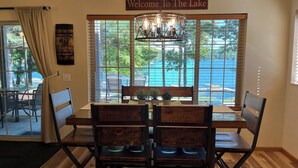 Un comedor con vista a un lago, un cartel que dice 'Welcome To The Lake' y una araña.