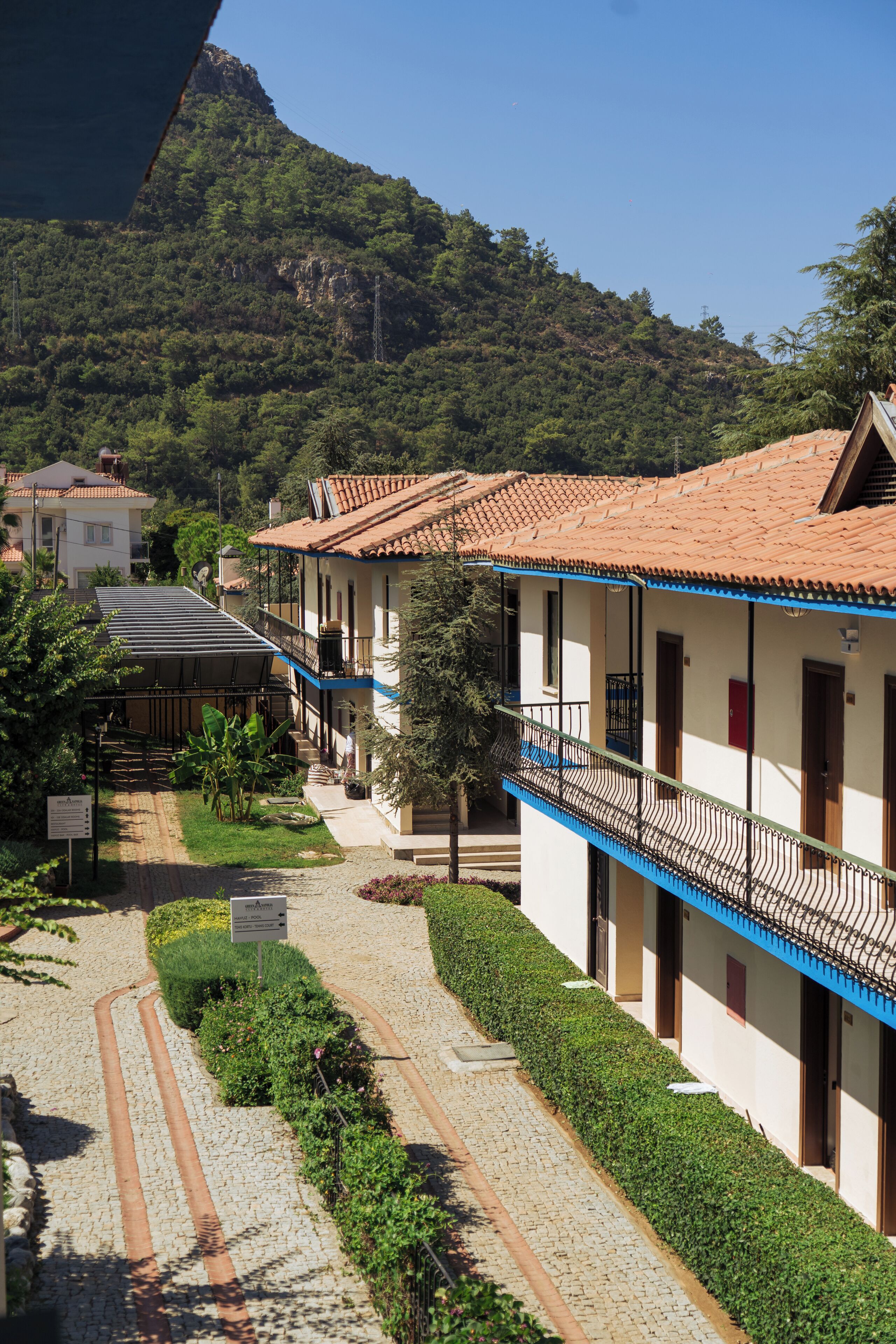 Un hotel con tejado de tejas, balcón y vistas a la montaña.