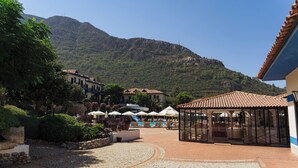 Une cour avec un sol carrelé, un espace de repos abrité et une montagne en arrière-plan.