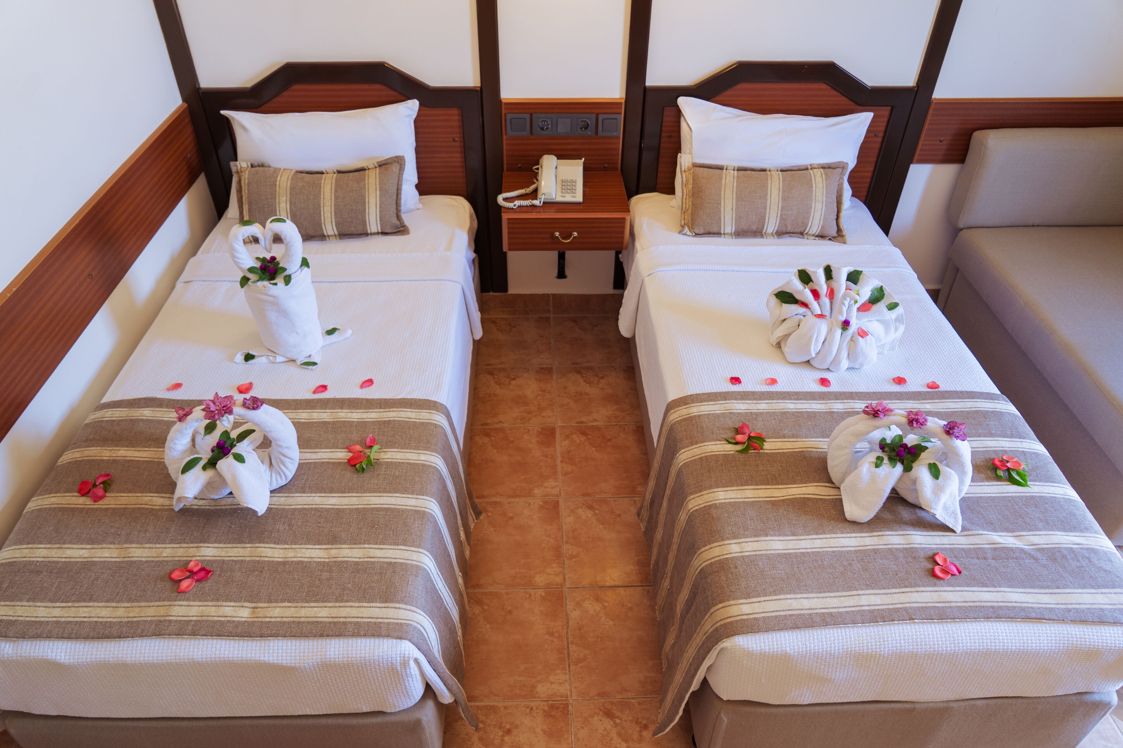 Een hotelkamer met twee bedden, elk voorzien van een houten hoofdbord, nachtkastje en telefoon.