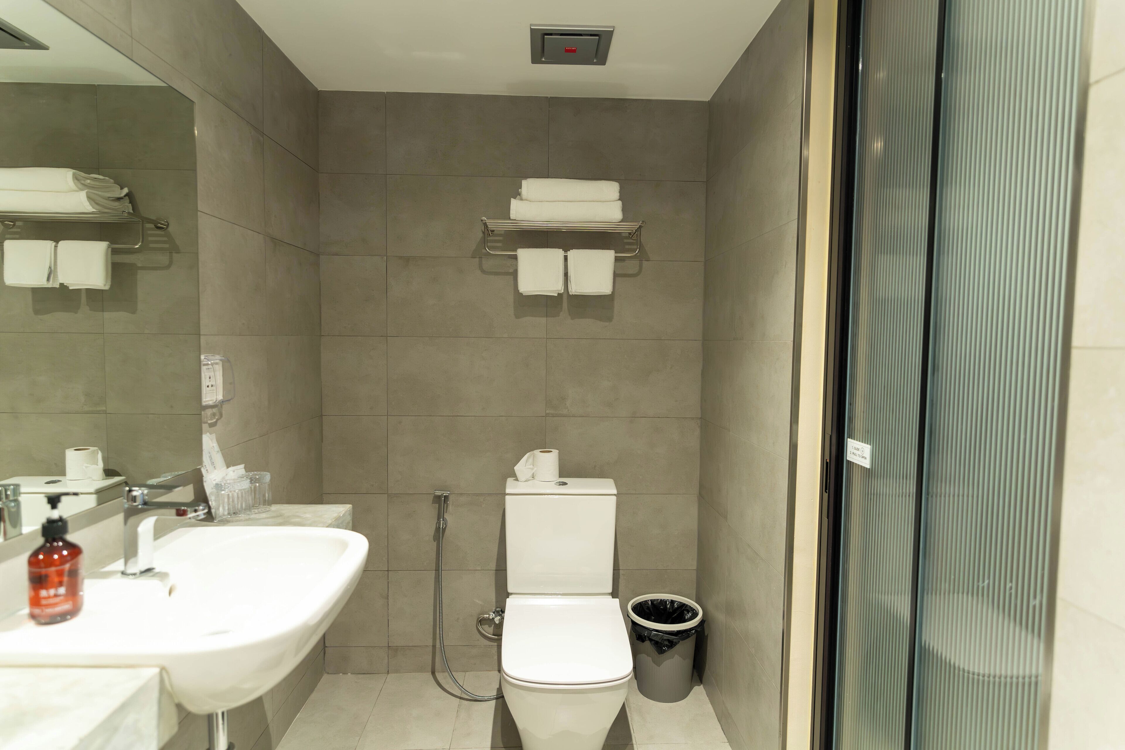Een moderne badkamer met een wastafel, toilet en douchecabine met glazen wanden.
