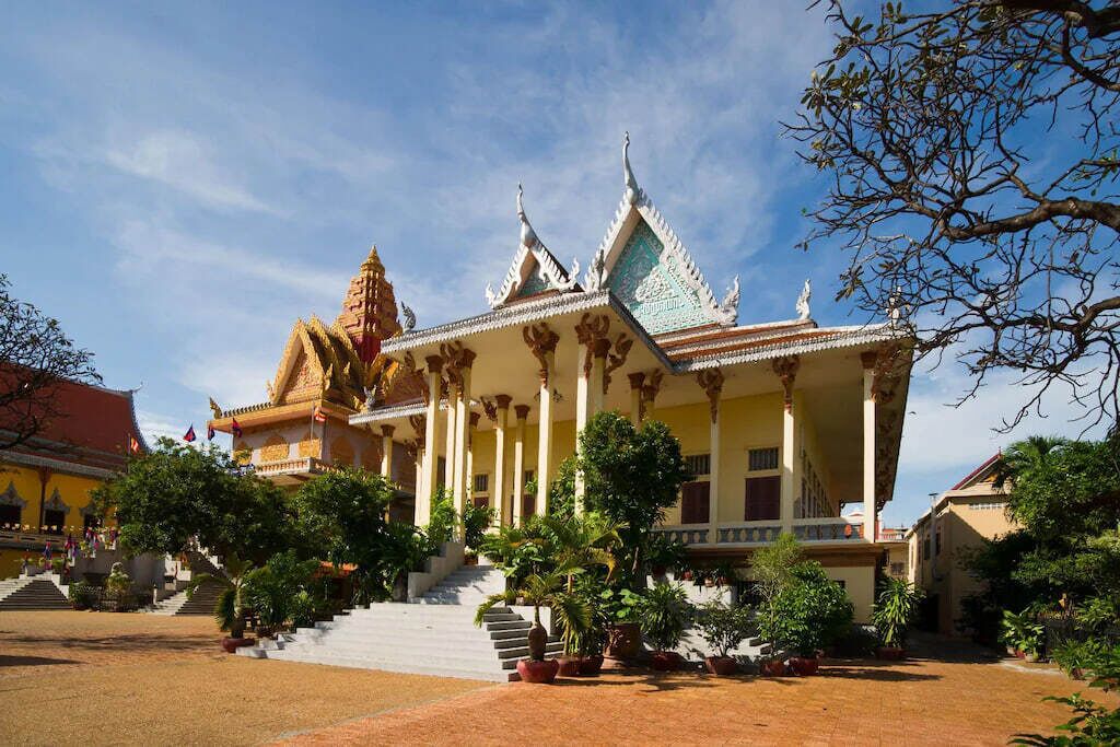 A traditional temple with a multi-tiered roof, a central staircase, and a courtyard with potted plants.