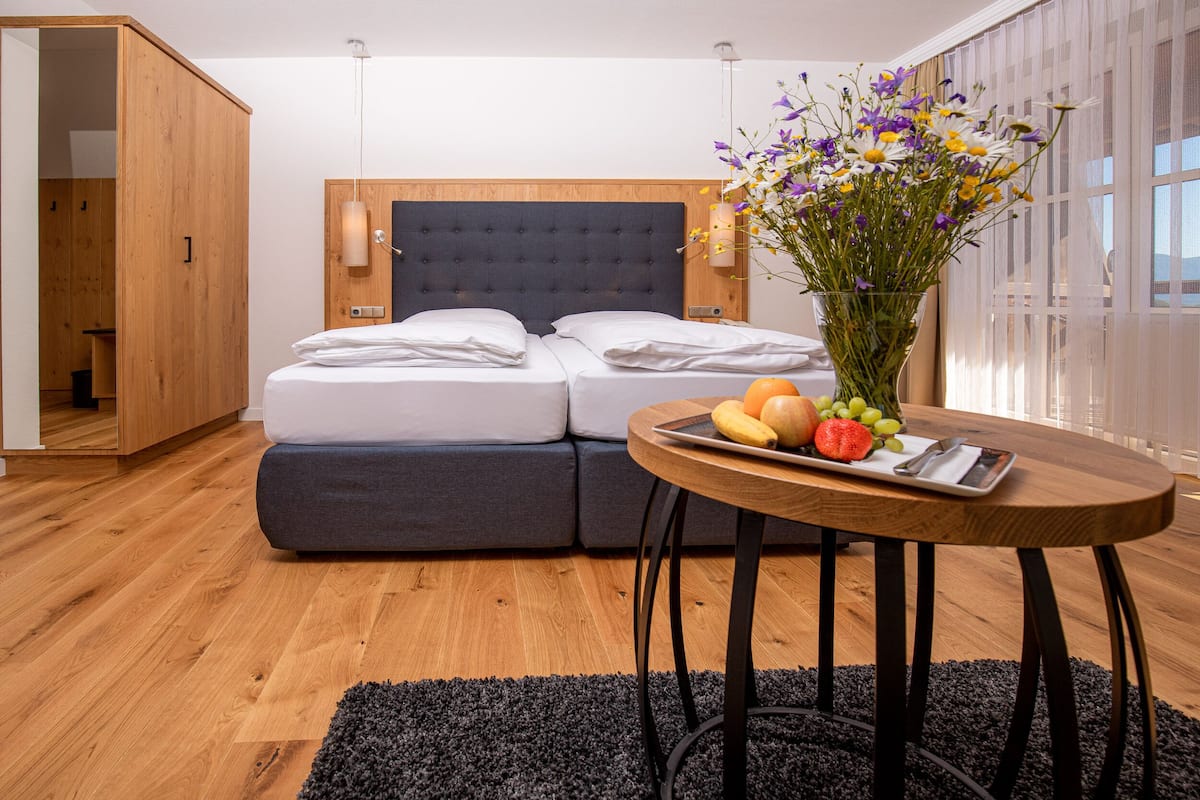 A modern bedroom with a bed, a bedside table with fruit, and a vase of flowers.