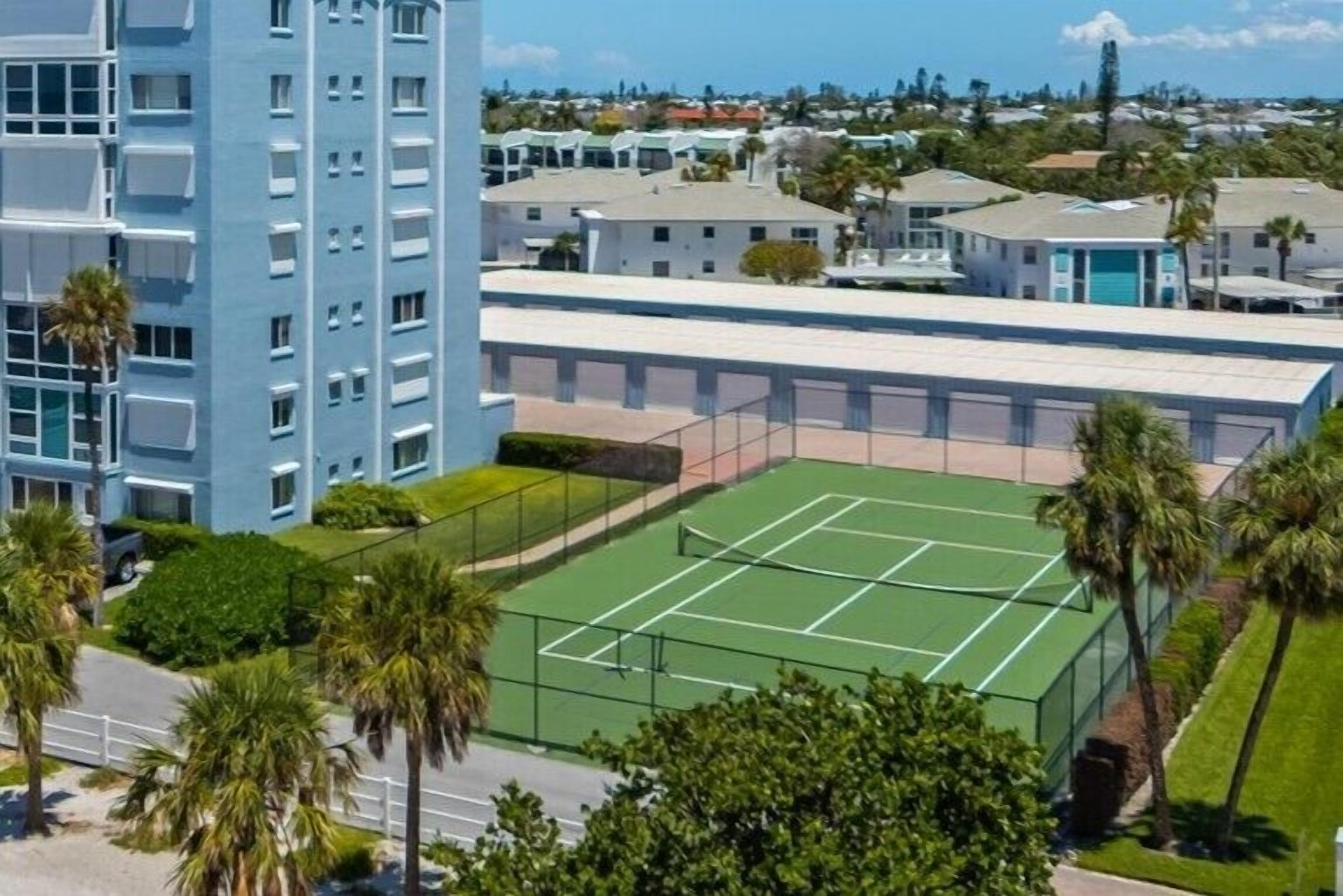 Un edificio de varios pisos con una cancha de tenis al frente.