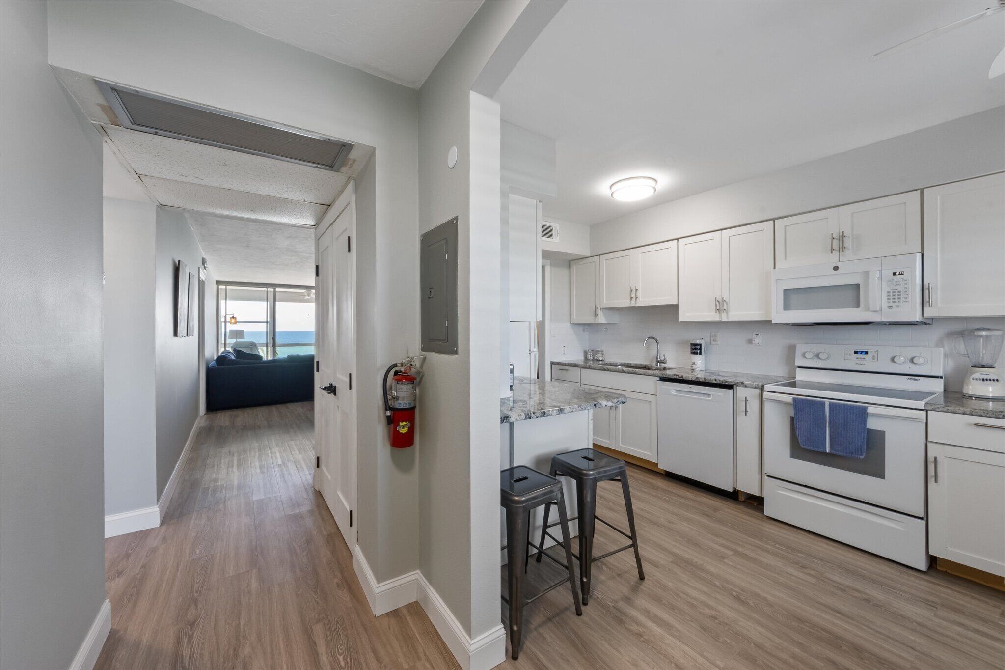A modern kitchen with white cabinets, a microwave, an oven, and a built-in island with stools.