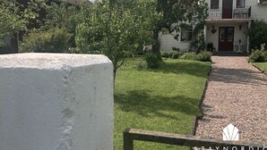 A white house with a red door, a gravel driveway, and a garden with trees and shrubs. - Charming and spacious villa near Lidköping |SE08085 (Lidköping)