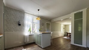 A spacious kitchen with a central island, a dining area with a table and chairs, and a view of the adjacent room. - Charming and spacious villa near Lidköping |SE08085 (Lidköping)