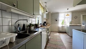 A modern kitchen with stainless steel appliances, a double sink, and a window with a view of greenery. - Charming and spacious villa near Lidköping |SE08085 (Lidköping)
