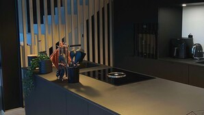 Una cocina moderna con una isla central, luces colgantes y estufa empotrada.