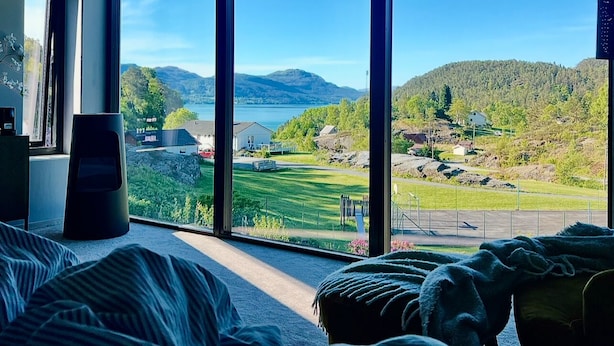 Un dormitorio con ventanas amplias que ofrecen vistas a un lago, montañas y un pueblo.