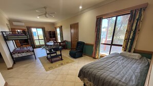 A room with a bed, a futon, a foosball table, a chair, and a window with curtains.