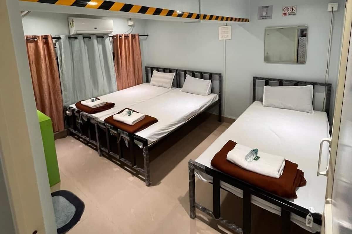 A hotel room with two beds, a bathroom, and a small sitting area.