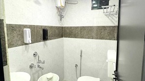 A bathroom with two sinks, a toilet, a shower, and a hand dryer. - Mama Lodging and Boarding (Margao)
