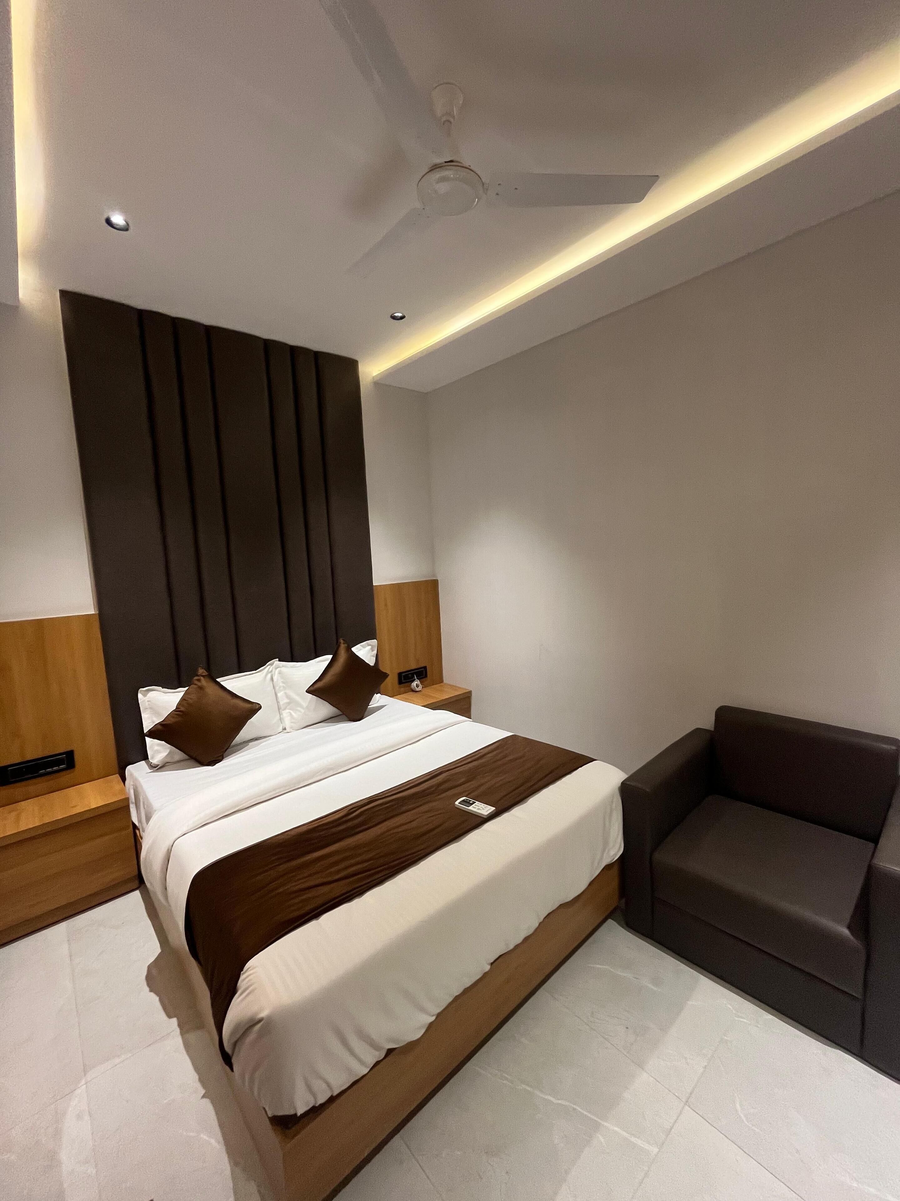 Une chambre d’hôtel moderne avec un grand lit, une table de chevet, une chaise et un ventilateur de plafond.