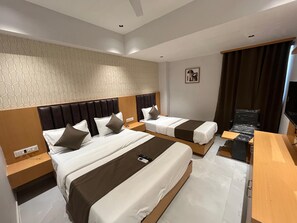 A hotel room with two beds, a wooden headboard, a small table, and a TV. - Hotel Pulse Town (Ahmedabad)