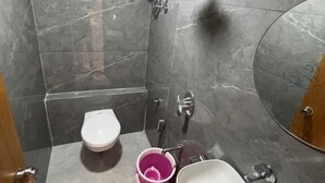A bathroom with a toilet, sink, and shower area. - Hotel Pulse Town (Ahmedabad)