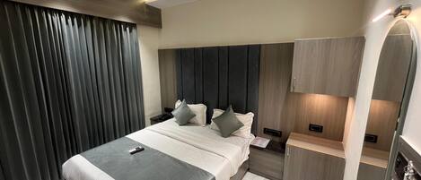 Una habitación de hotel moderna con una cama grande, mesitas de noche, un escritorio y un espejo.
