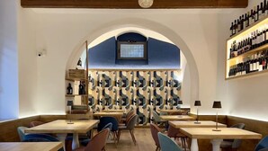 A restaurant with wooden tables and chairs, a patterned wall, and a wine rack. - La Torre del Nostromo (Salerno)
