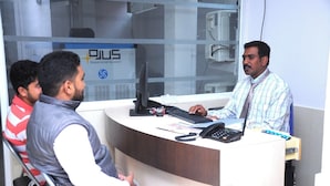 A reception desk with a computer, phone, and papers. - Brindavan Service Apartments (Mysore)