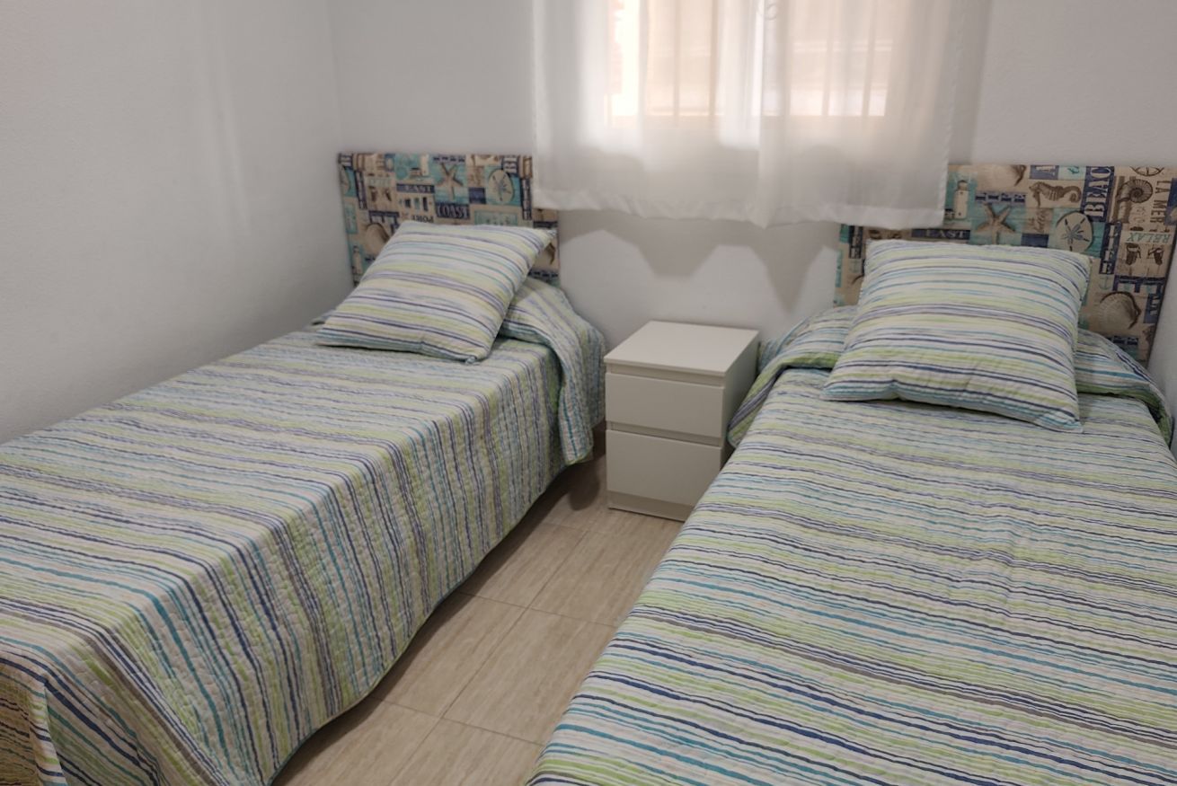 A small, single-room accommodation with two beds, each with striped bedding.