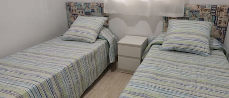 Un alojamiento pequeño, una habitación individual con dos camas, cada una con ropa de cama a rayas.