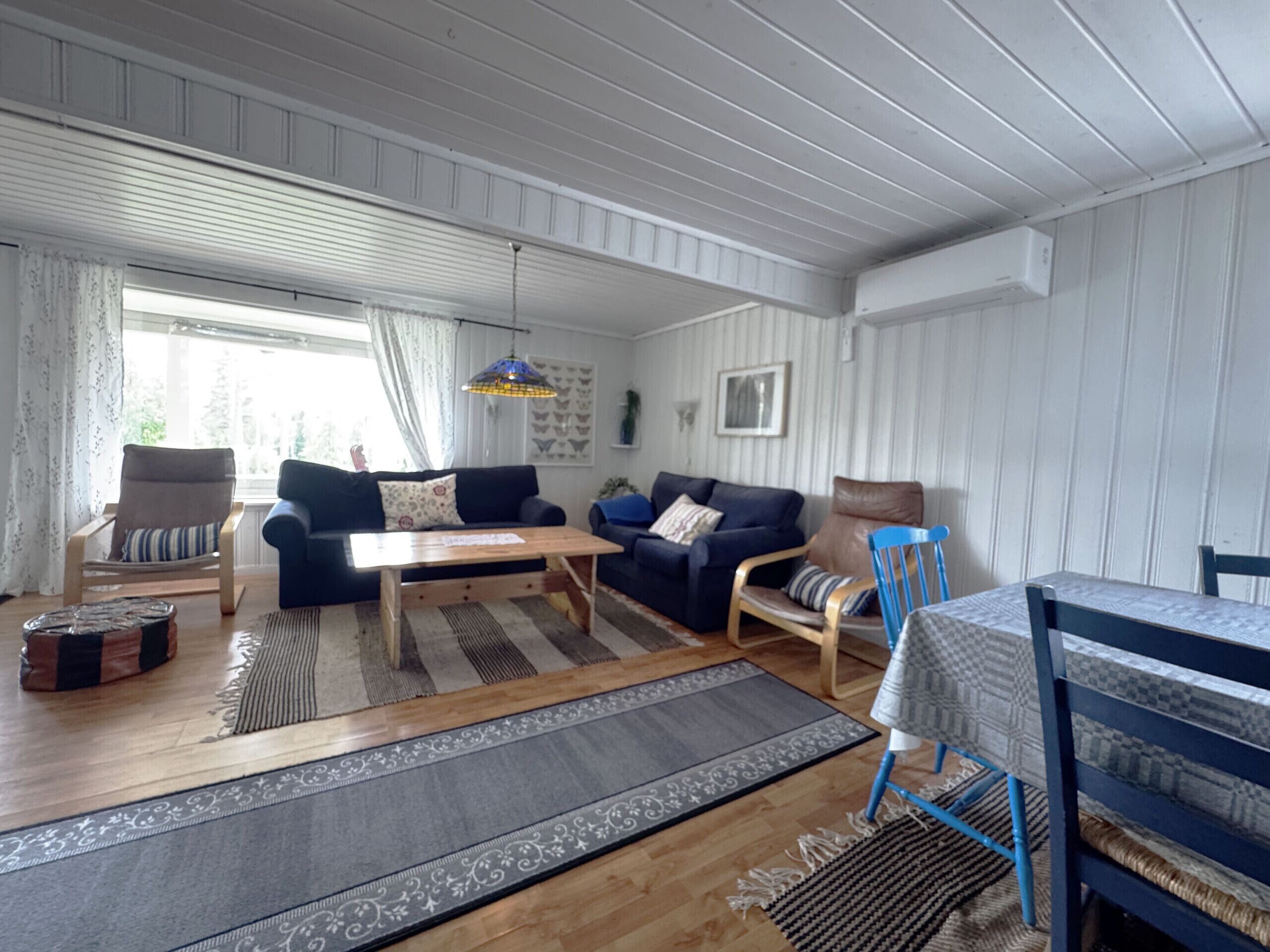 A cozy living room with a wooden floor, a blue sofa, a wooden coffee table, and a blue chair.