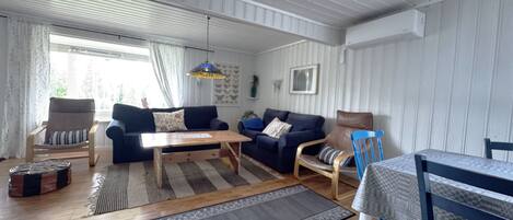 A cozy living room with a wooden floor, a blue sofa, a wooden coffee table, and a blue chair.