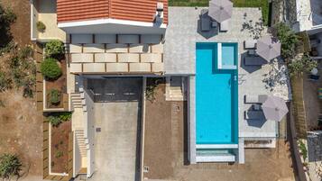 Una casa moderna con piscina, mobiliario exterior y jardín.