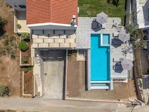 Une maison moderne dotée d’une piscine, d’un espace salon extérieur et d’un jardin.