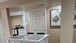 A kitchen with a white island, beige walls, and a wooden floor. - Modern 2BR Basement Suite with Jacuzzi  Access, Full Kitchen & Free Wifi (Roosevelt)