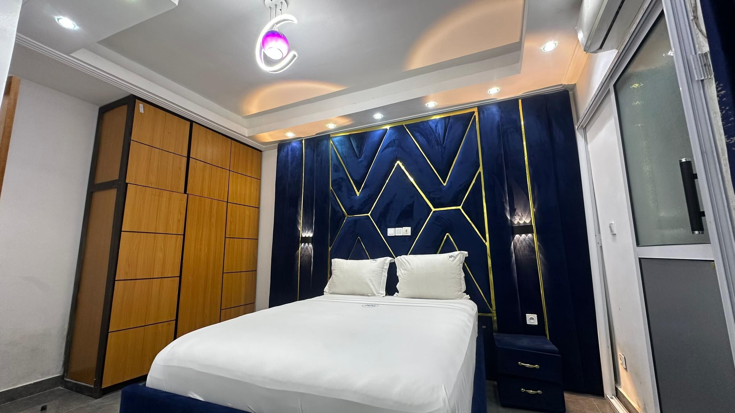 A modern bedroom with a bed, a wardrobe, and a vanity with a mirror.