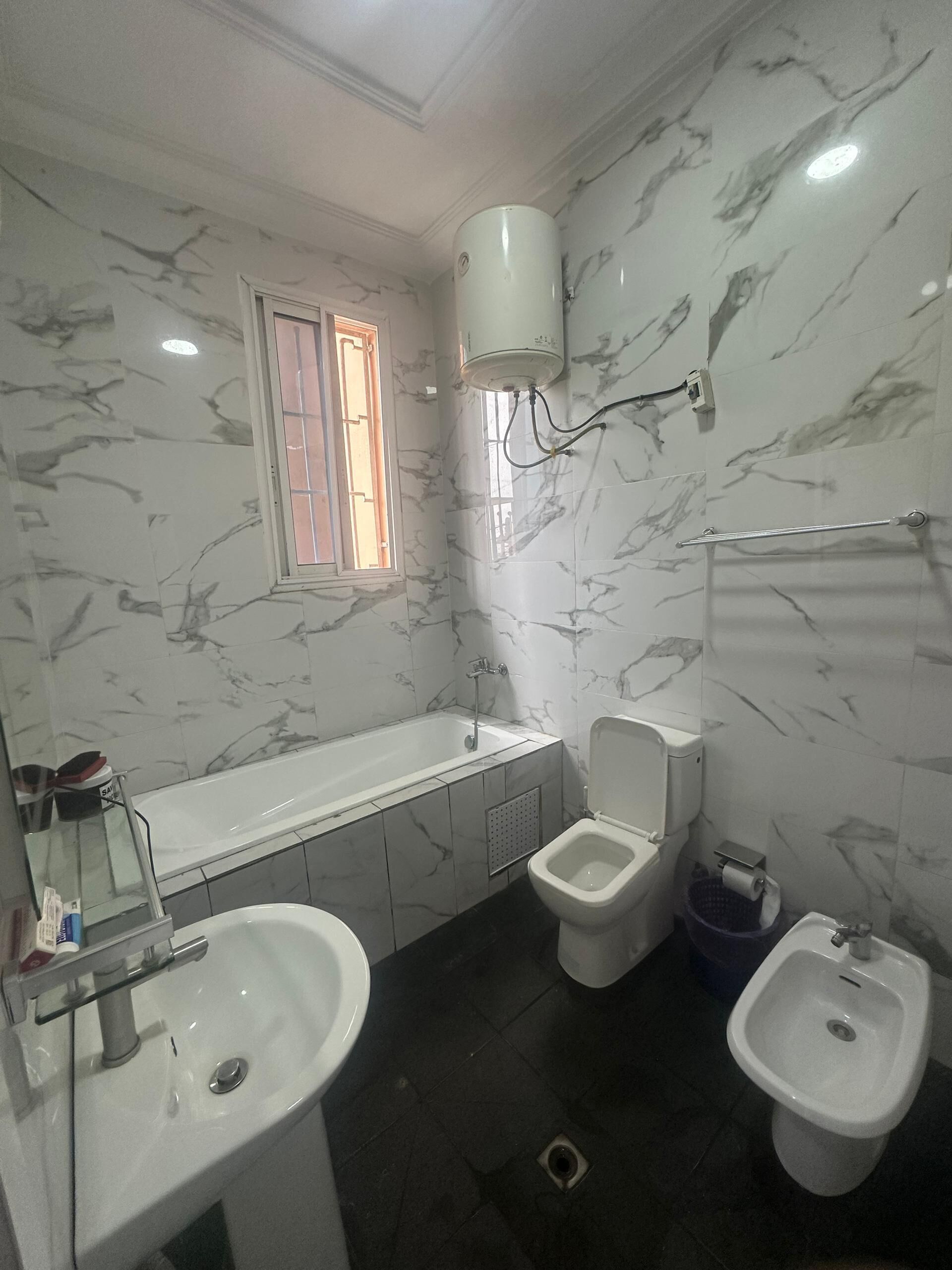 A bathroom with a bathtub, two sinks, a toilet, and a bidet.