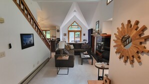 A spacious living area with a high ceiling, a fireplace, and a staircase leading to an upper level. - Multi-level, open concept, AC, wooded view, deck, swim club. F1602 by LRS (Lincoln)