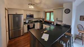 A modern kitchen with stainless steel appliances, a large island, and a window providing natural light. - Multi-level, open concept, AC, wooded view, deck, swim club. F1602 by LRS (Lincoln)