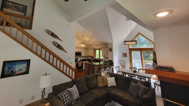 A spacious living area with a high ceiling, a ceiling fan, a dining area, and a kitchen visible through an open doorway. - Multi-level, open concept, AC, wooded view, deck, swim club. F1602 by LRS (Lincoln)