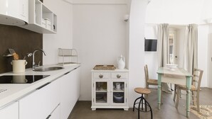 A compact kitchen with white cabinetry, a built-in stove, and a dining area with a table and chairs.