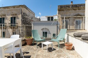 A rooftop terrace with two chairs, a table, and potted plants. - Terrazza Panoramica Cavour by Wonderful Italy (Ostuni)