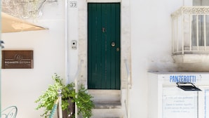 A building with a green door, a sign reading "RICANATI OSTERIA," and a sign with "PANZEROTTI" on it.