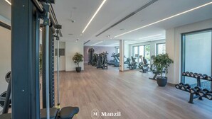 Une salle de sport moderne équipée de matériel d’exercice, dotée de revêtements de sol en bois et de grandes fenêtres.